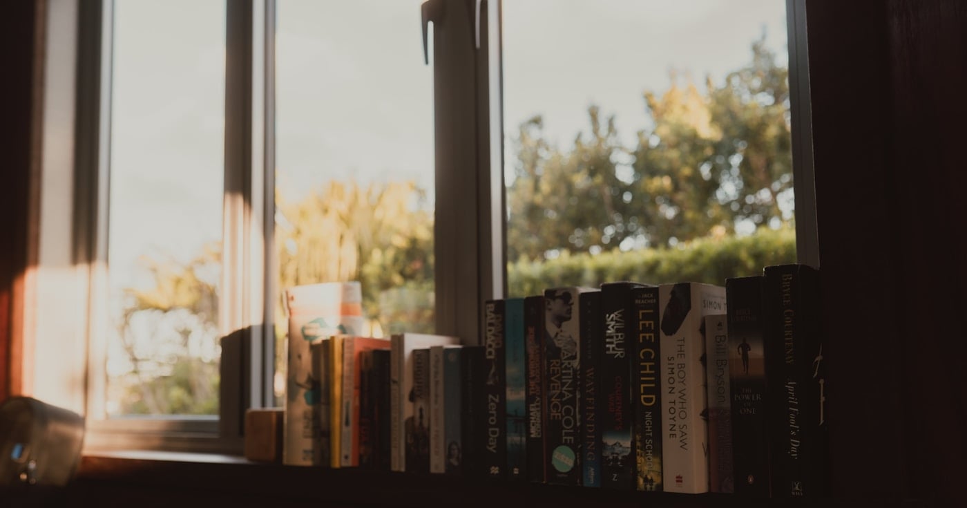 Books on a windowsill bathed in warm sunlight