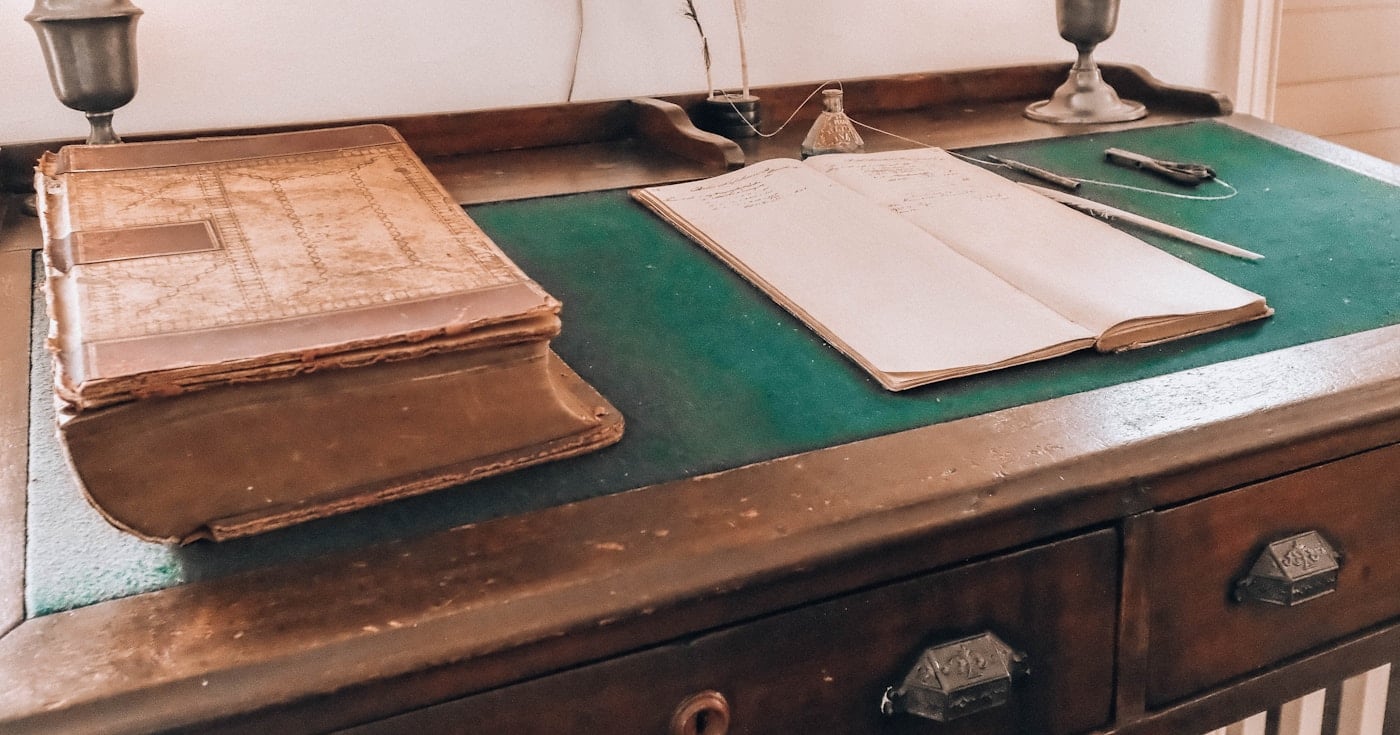 Open book with quill on antique writing desk — visual representing literary allusion