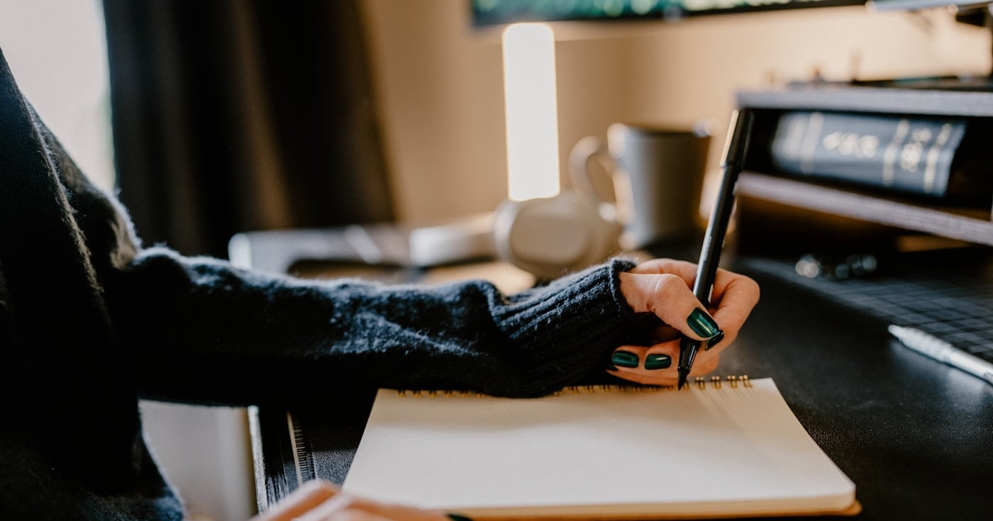 Person writing in a notebook at a desk