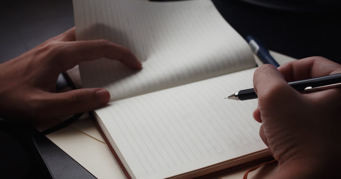 Person writing in a notebook to improve their writing skills