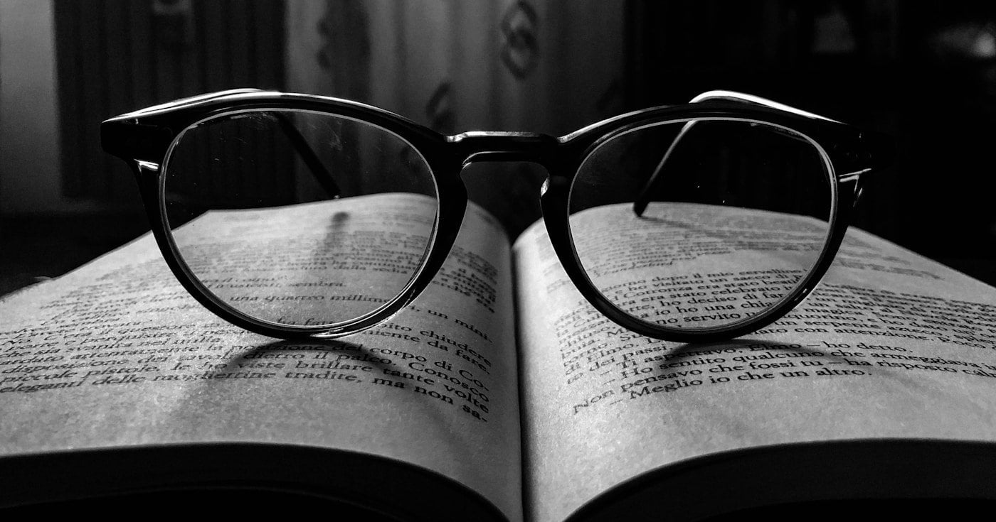 Glasses resting on an open book — a visual metaphor for the contrast at the heart of irony