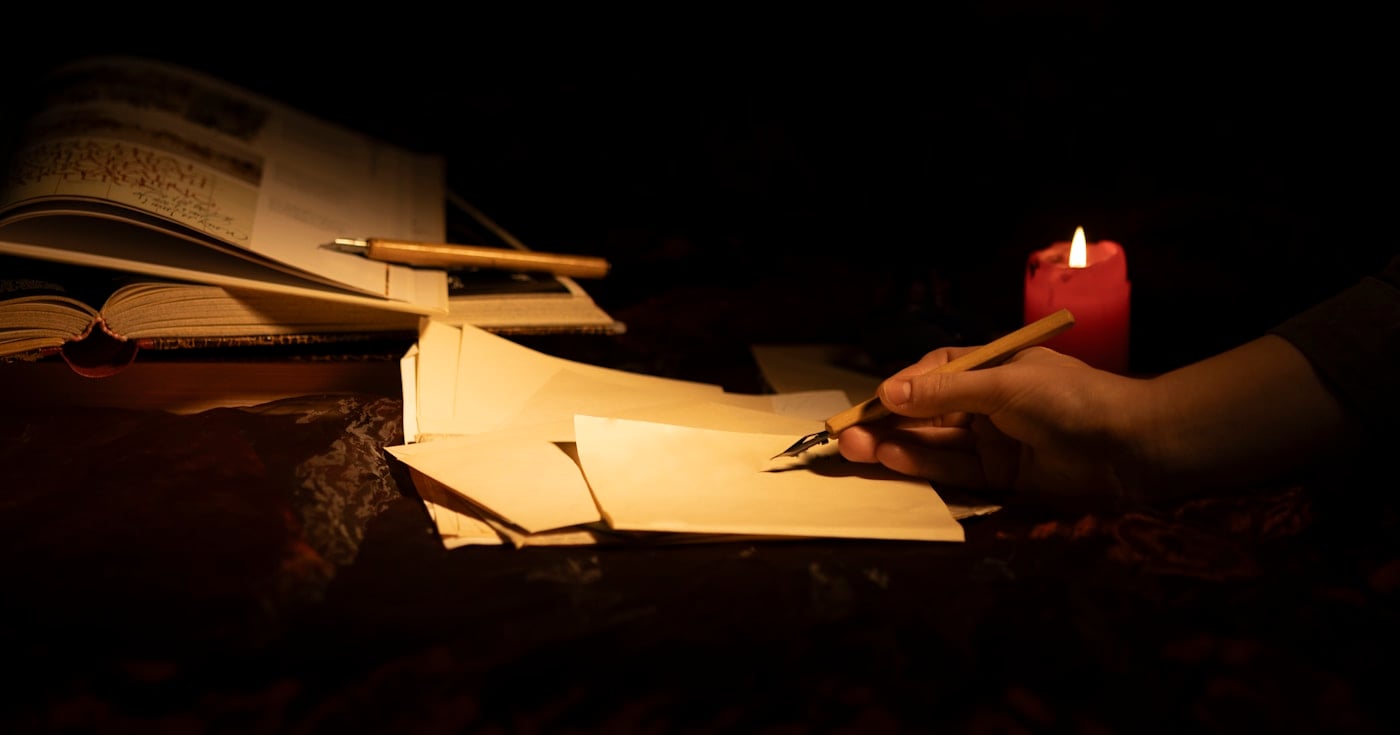 Person writing by candlelight, evoking the craft of literary language