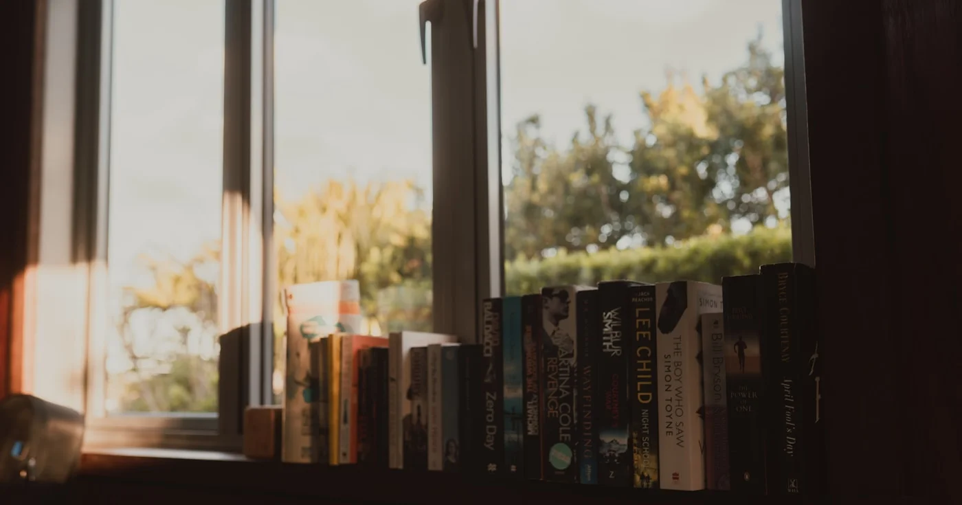 Books on a windowsill bathed in warm sunlight