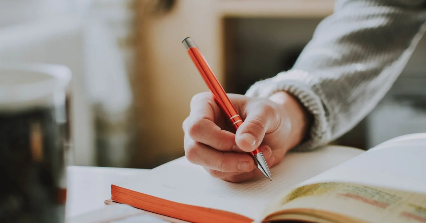 Person writing in notebook, practicing grammar and sentence structure