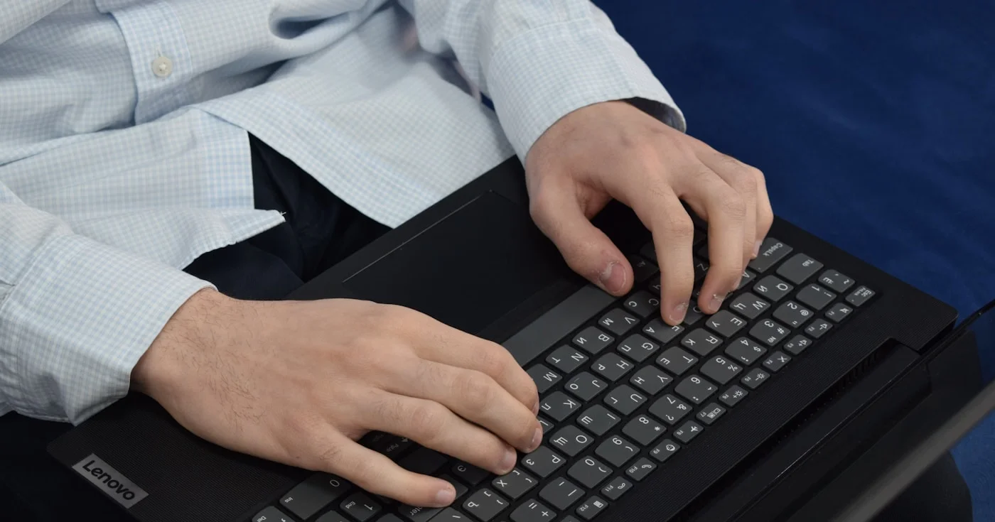 Person typing on laptop keyboard for technical writing